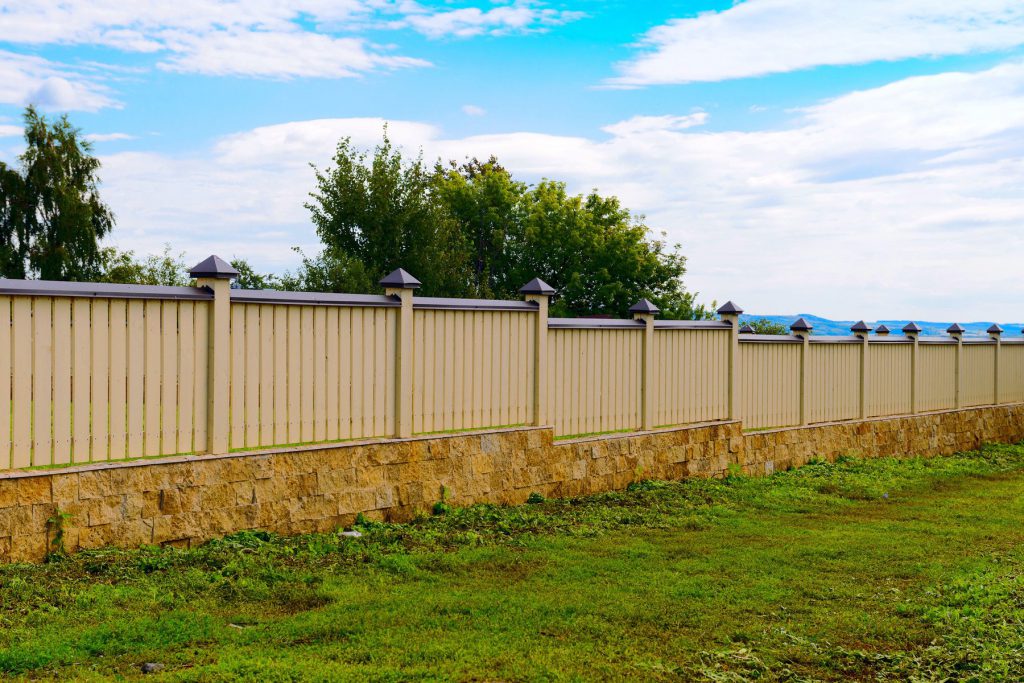 A painter applying stain to a cedar fence board