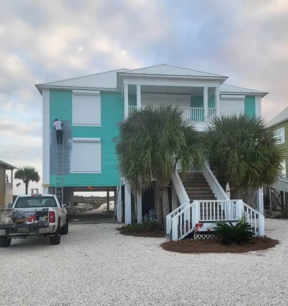 Exterior Beach House Painting Service with Teal and Gray Colors Painter working on the exterior of a Gulf Coast home