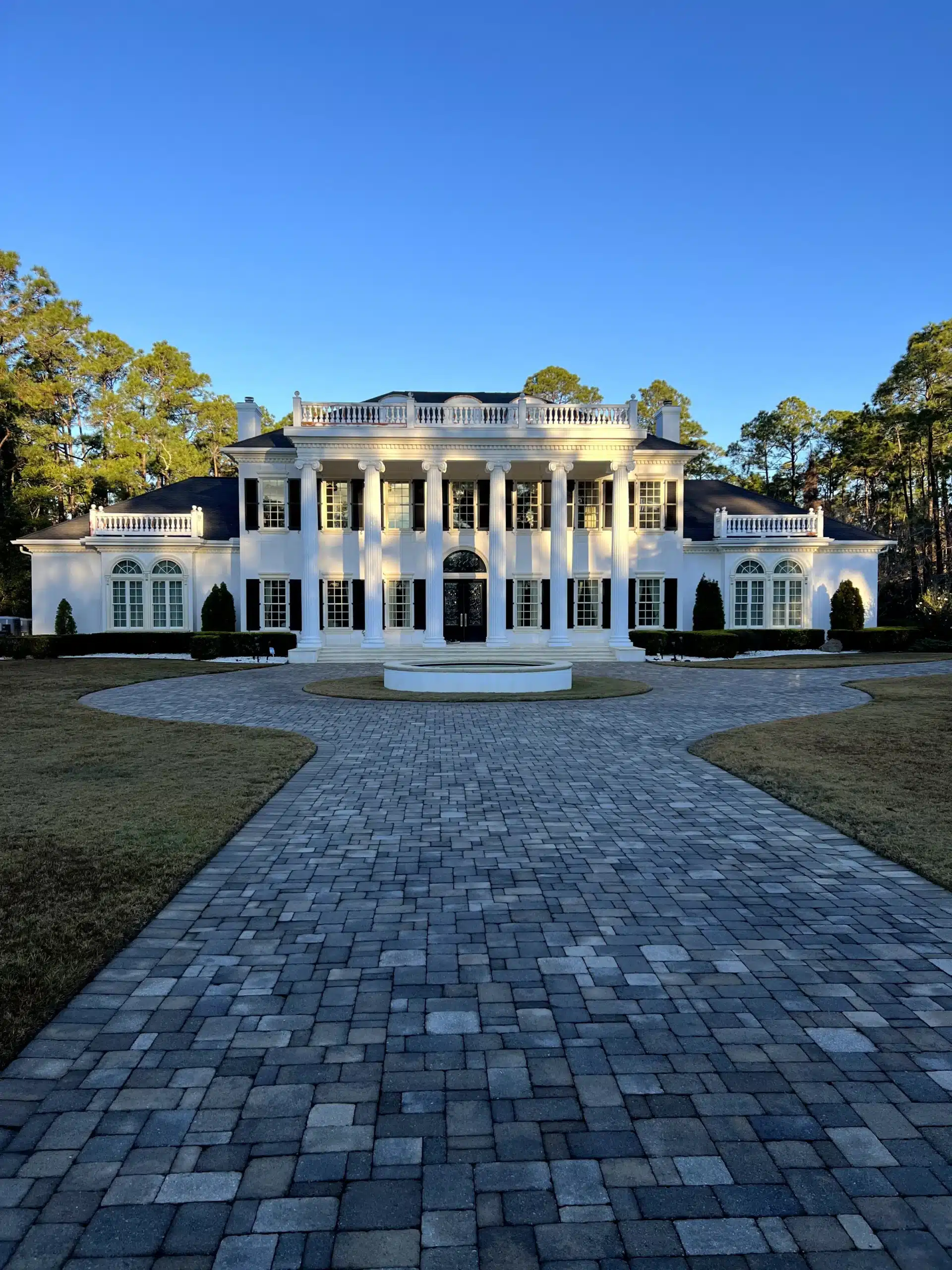 Luxury Residential Exterior Painting Services A magnificent white mansion with classical columns and a circular driveway, showcasing expert exterior house painting.