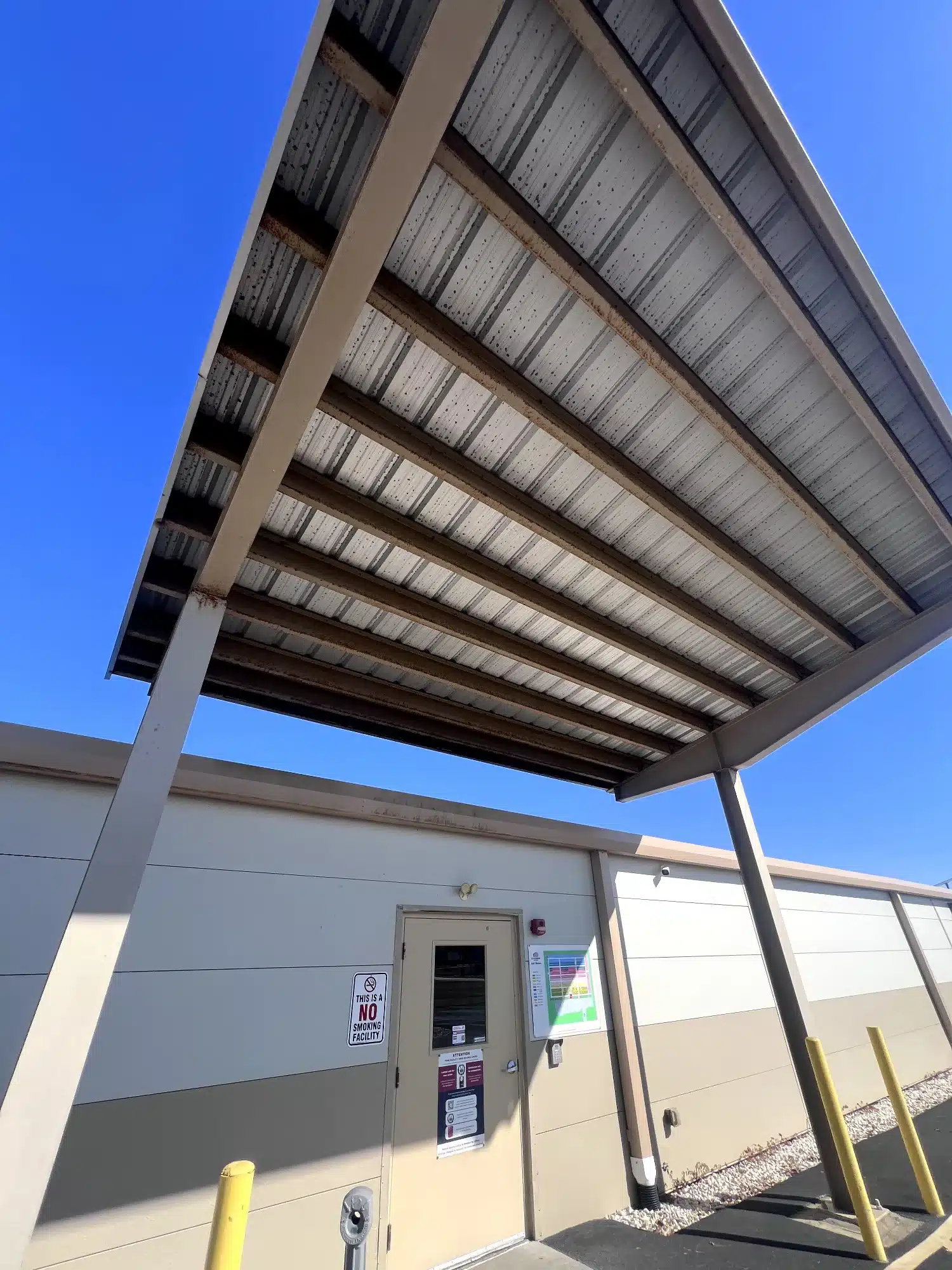 Commercial Building Exterior Coating Light gray painted commercial building exterior with metal roof overhang and corrugated panels